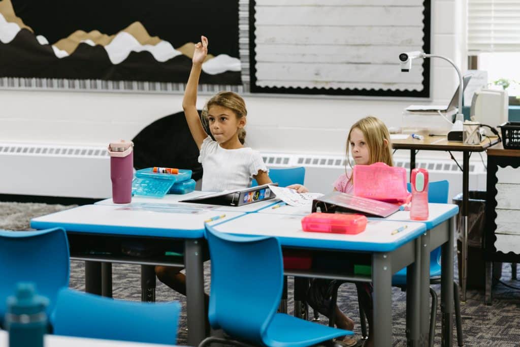 A student raising their hand in class to answer a question