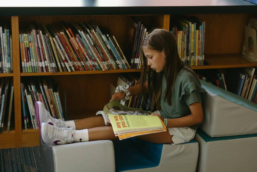 A middle schooler reading a book in a library