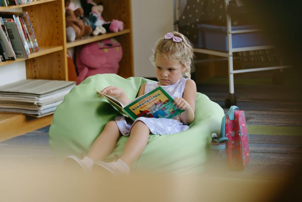 A student sitting on a bean bag engaged in a book