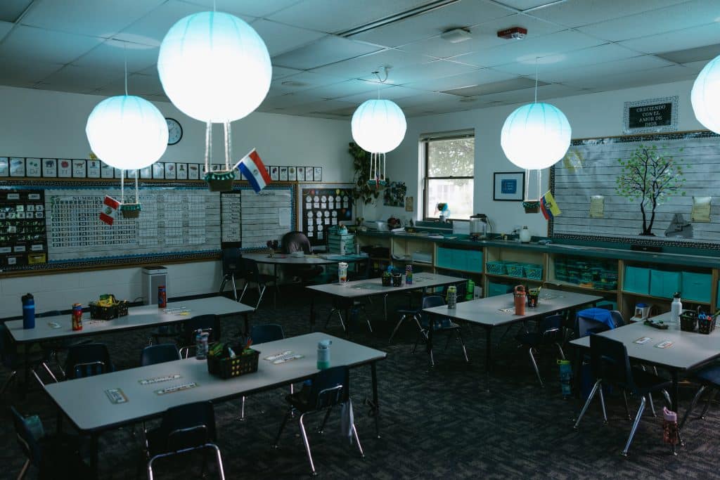 A classroom with the lights down low and globe lights made of paper glow as they hang from the ceilings
