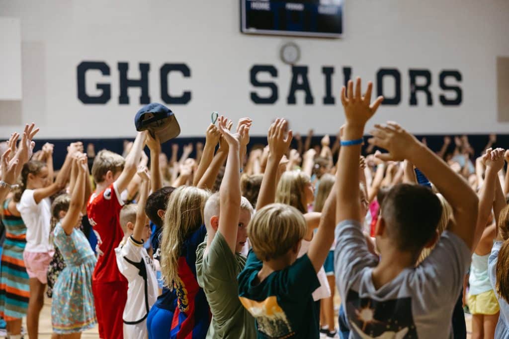 Image of students in a group with their arms in the air