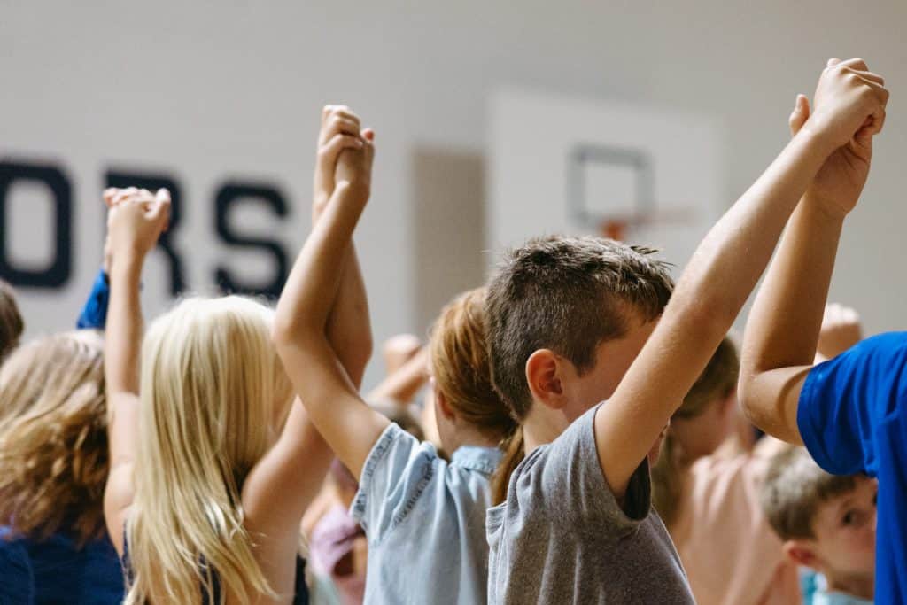 Image of students holding hands in a group with their arms in the air